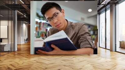 asian male student reading book in university Wall mural