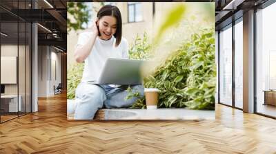 Asian woman sitting outdoors using laptop computer Wall mural