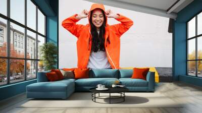 Attractive smiling young asian woman wearing raincoat Wall mural