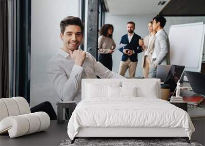 Attractive young confident businessman sitting at the office Wall mural