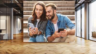 Attractive young couple sitting on stairs outdoors Wall mural