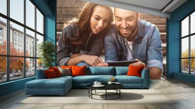 Attractive young couple sitting on stairs outdoors Wall mural