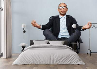 Attractive young man in glasses meditating on office chair Wall mural