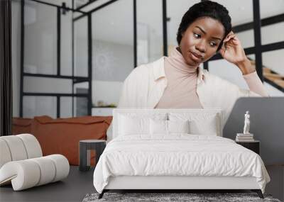 Attractive young smiling african woman sitting on a couch Wall mural