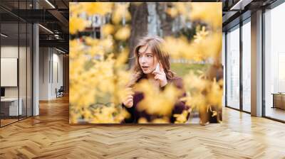 Attractive young woman talking on cell phone in park Wall mural