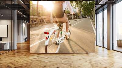 Back view image of young lady on bicycle on the street. Wall mural