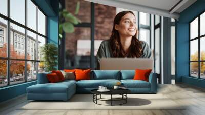 Beautiful smiling woman working with laptop while sitting at table Wall mural