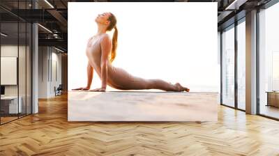 Beautiful woman outdoors on beach make stretching exercise. Wall mural