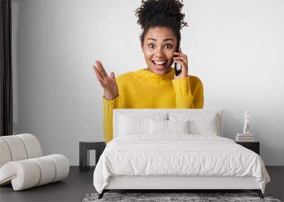 Beautiful young african excited emotional happy woman posing isolated over white wall background talking by mobile phone. Wall mural