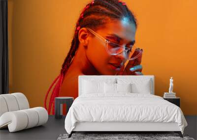 Beautiful young african naked woman posing isolated over yellow neon lights wall background wearing sunglasses. Wall mural