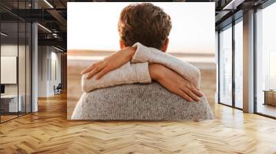 Beautiful young couple standing at the sunny beach Wall mural