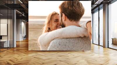 Beautiful young couple standing at the sunny beach Wall mural