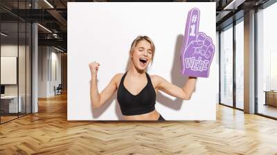 Beautiful young fitness woman isolated over white wall background holding number one glove fan. Wall mural