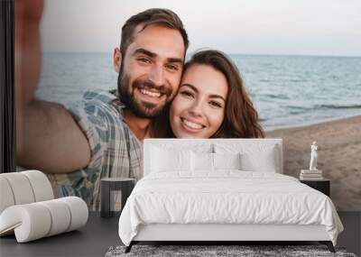 Beautiful young smiling couple spending time at the beach Wall mural