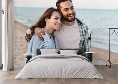 Beautiful young smiling couple spending time at the beach Wall mural