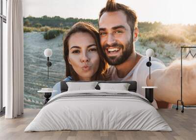 Beautiful young smiling couple spending time at the beach Wall mural