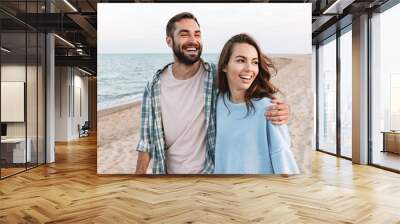 Beautiful young smiling couple spending time at the beach Wall mural