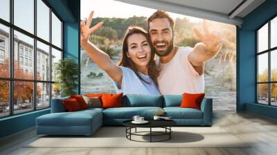 Beautiful young smiling couple spending time at the beach Wall mural