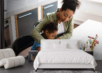 Black woman drawing with her happy daughter at home kitchen Wall mural