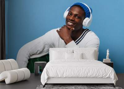 Black young man in headphones smiling and sitting on floor Wall mural