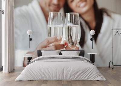 Blurry image closeup of caucasian handsome man and beautiful asian woman, holding and clinking glasses with champagne at hotel room Wall mural