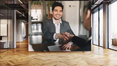 Business, career and placement concept - happy caucasian man 30s rejoicing and shaking hands with employee, when was recruited during interview in office Wall mural