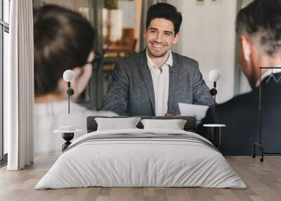 Business, career and placement concept - young caucasian man smiling, while sitting in front of directors during corporate meeting or job interview Wall mural