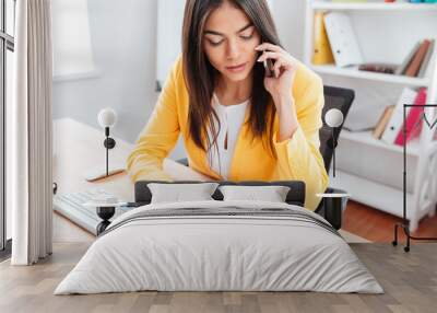 Businesswoman talking on the phone and analysing graphics Wall mural