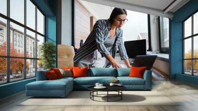 Charming focused woman working with laptop while standing at table Wall mural