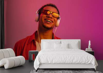 Cheerful african man listening music with headphones isolated over multicolored neon background Wall mural