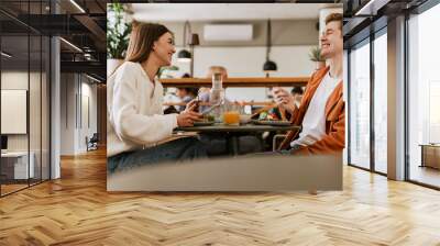 Cheerful couple having lunch together while sitting in cafe Wall mural