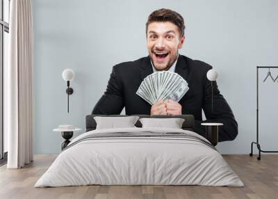 Cheerful excited young businessman laughing and holding money Wall mural