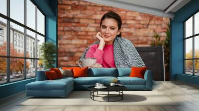 Cheerful girl smiling and drinking coffee while sitting in cafe Wall mural