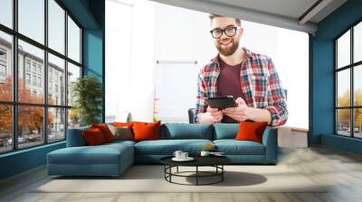 cheerful male sitting and holding tablet in the office Wall mural