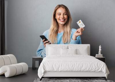 Cheerful young blonde girl in blue sweatshirt Wall mural