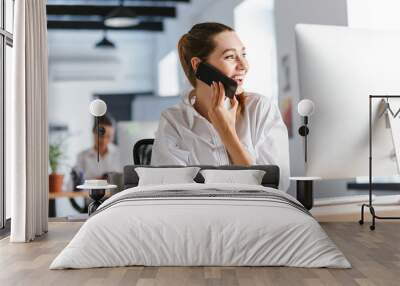 cheerful young businesswoman sitting at her workplace Wall mural