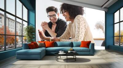 Cheerful young colleagues using laptop computer together Wall mural