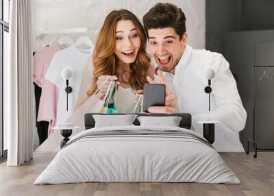 Cheerful young couple shopping for clothes together Wall mural