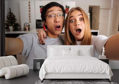 Cheerful young couple sitting on a couch at home Wall mural