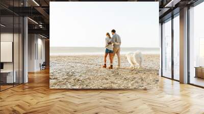 Cheerful young couple walking at the beach Wall mural