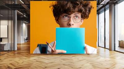 Cheerful young male student holding books isolated Wall mural