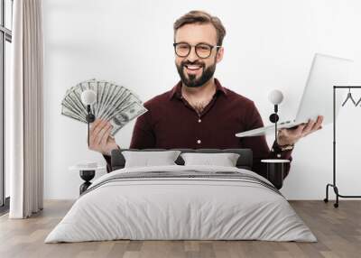 Cheerful young man holding money and laptop computer. Wall mural