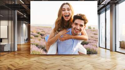 Cheery young couple having fun at the lavender Wall mural