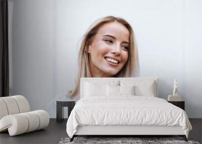 Close up of a smiling young blonde woman standing Wall mural