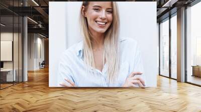 Close up of a smiling young blonde woman standing Wall mural