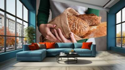 Close up photo of female baker holding bag with bread Wall mural