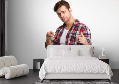 Close-up photo of serious young guy in checkered shirt pointing with two fingers, looking at camera Wall mural