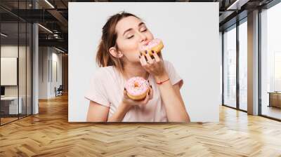 Close up portrait of a satisfied pretty girl eating donuts Wall mural