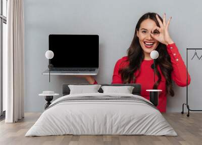 Close-up portrait of happy attractive woman showing empty laptop display, looking looking through OK gesture Wall mural