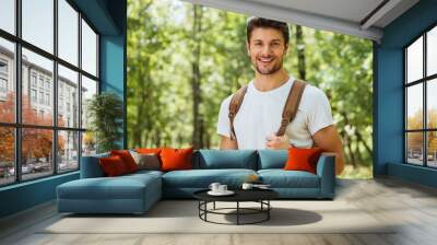 closeup of cheerful young man standing and smiling in forest Wall mural